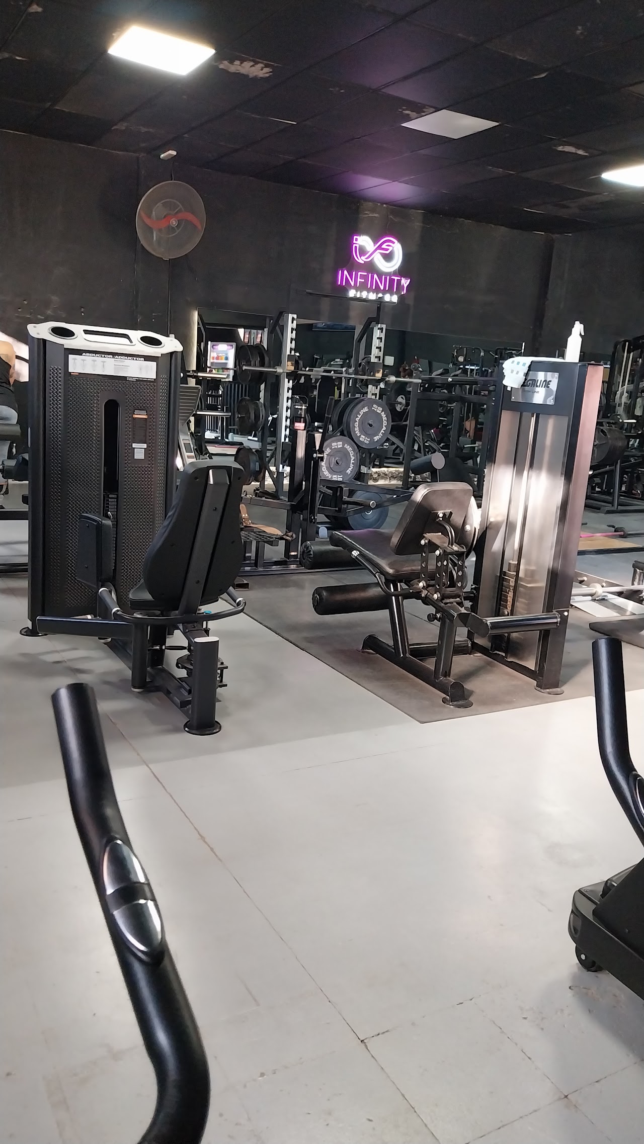 Interior moderno de Infinity Fitness Neuquén con barras, mancuernas e iluminación de neón
